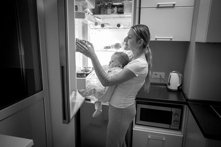 年轻母亲和小儿子在冰箱里寻找食物的黑白画面图片
