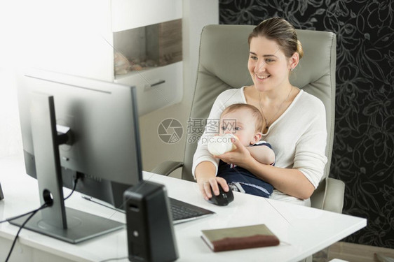 带9个月婴儿的漂亮女人在家工作图片