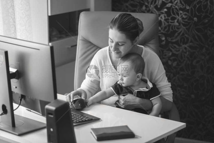 带着婴儿坐在办公室的微笑年轻母亲黑白画像图片