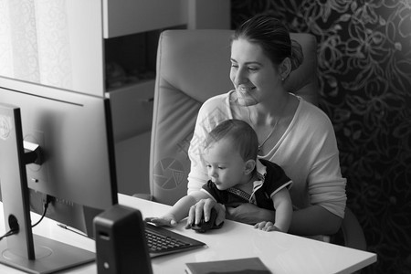 黑人和白的画面快乐笑女人在计算机工作与她的小宝贝儿子图片