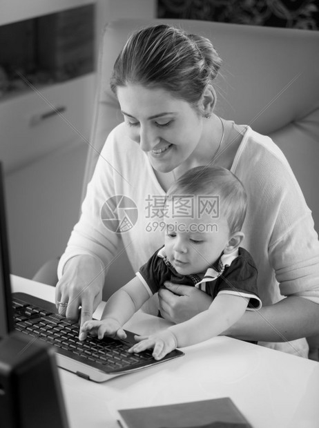 黑白小男孩坐在母亲的膝上并使用键盘的黑白小男孩画面图片