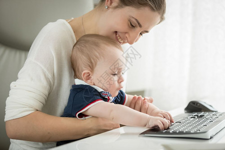 坐在母亲大腿上和键盘打字的可爱婴儿图片