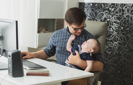 年轻人与婴儿一起坐在家里工作图片