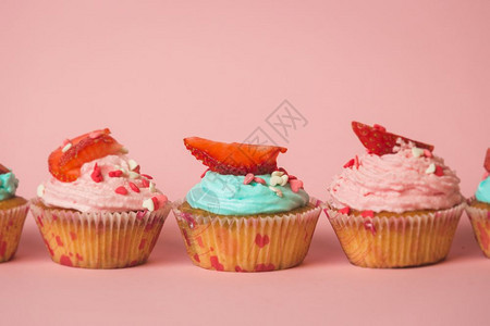 彩色纸杯蛋糕的剪贴照片上面有喷洒和新鲜草莓排成一行图片