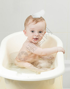 喜悦的男孩子坐在浴室里洗澡的肖像图片