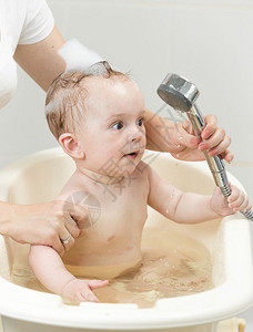 婴儿抓着淋浴头玩耍图片