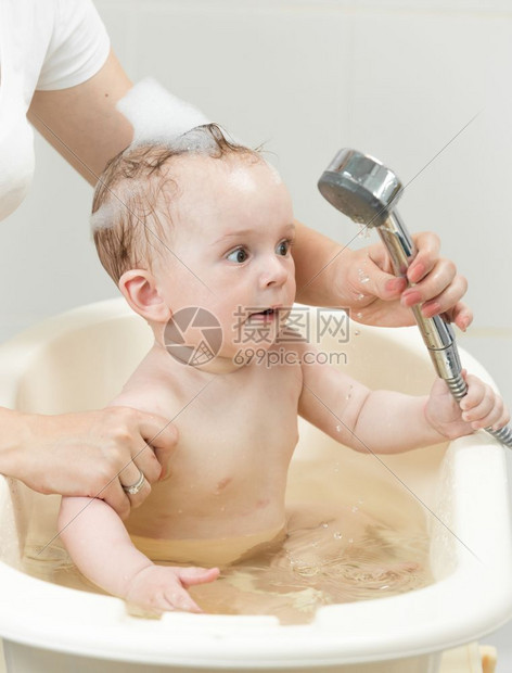 婴儿抓着淋浴头玩耍图片
