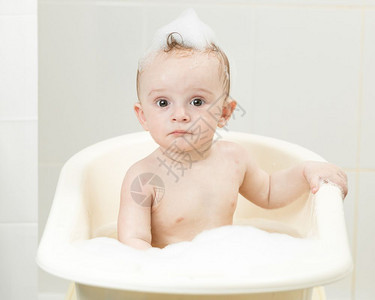 喜悦的男孩子坐在浴室里洗澡的肖像背景图片