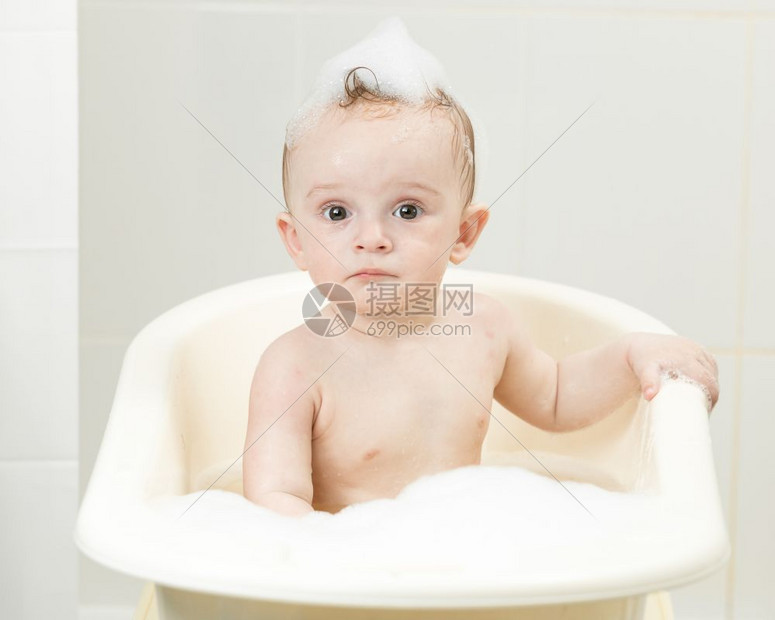 喜悦的男孩子坐在浴室里洗澡的肖像图片