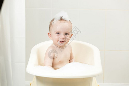 坐在浴缸里沾满泡沫的笑的男孩图片