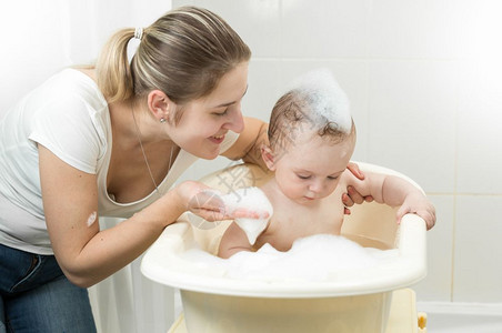 微笑的母亲在洗澡时与婴儿一起玩耍的肖像图片