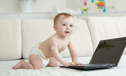可爱的婴儿爬在床上膝型电脑图片