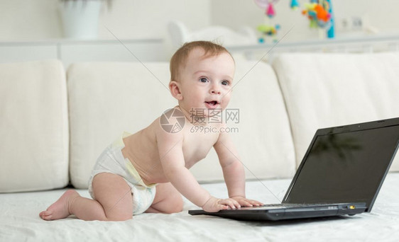可爱的婴儿爬在床上膝型电脑图片