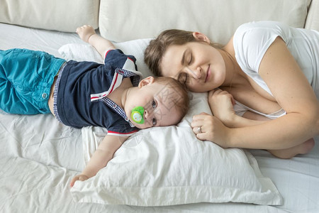 女人的肖像躺在枕头上与婴儿的子躺在枕头上图片