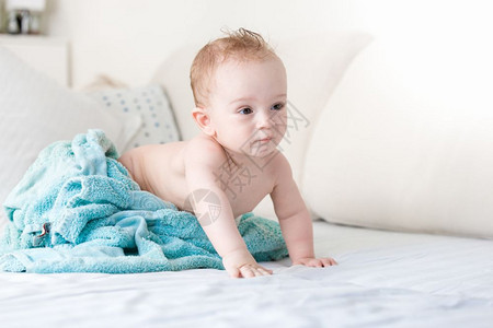 9个月的男孩婴儿蓝毛巾下睡在床上白单和图片