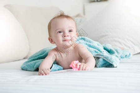 9个月大的婴儿在洗澡后蓝毛巾下躺床上图片