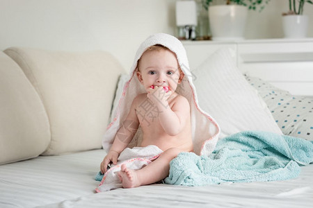 坐在床上的可爱婴儿被毛巾覆盖在床上图片