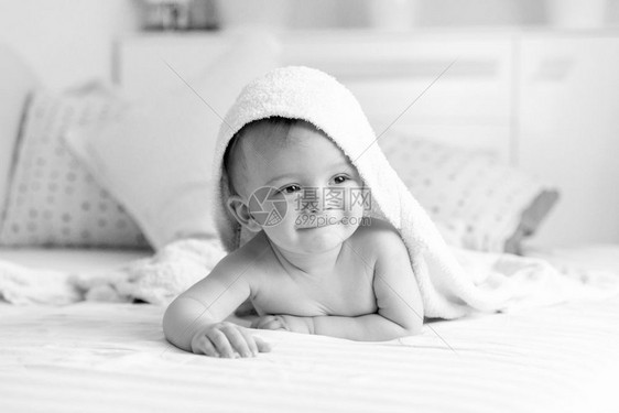 穿着毛巾躺在床上的快乐婴儿黑白肖像图片