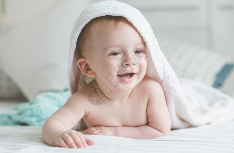 睡完澡后躺在床上的戴着毛巾可爱微笑婴儿图片
