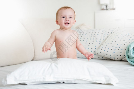 带着大枕头在床上玩耍时微笑的男孩图片