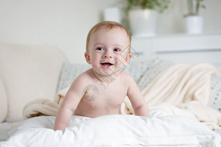 9个月大的快乐婴儿爬在床上枕头图片