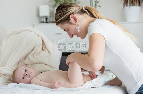 年轻母亲改变其婴儿男孩和尿布图片