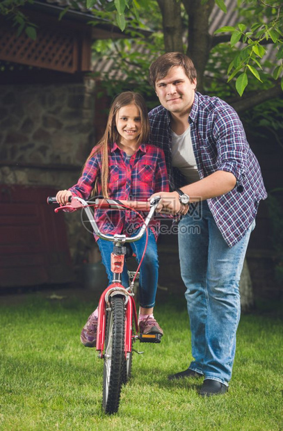 年轻父亲教女儿骑自行车图片
