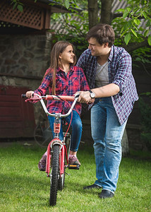 男人教可爱女孩如何在公园骑自行车图片