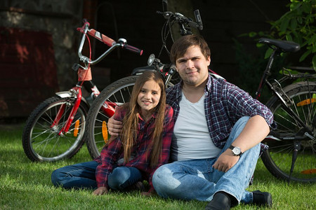 父亲带着女儿骑自行车在公园的草地上放松休息图片