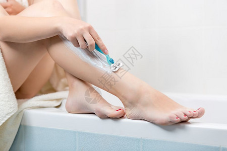 女青年在浴室刮腿毛的近视图像图片