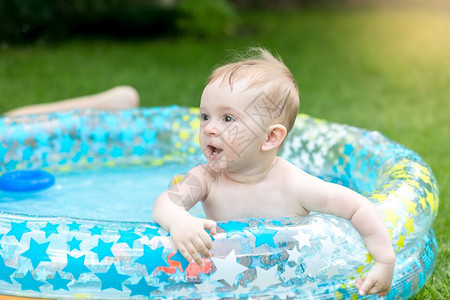 婴儿男孩在花园游泳池玩耍的肖像图片