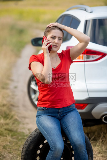 坐在备用轮胎上打电话呼救的女人图片