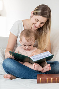 母亲和她九个月大的孩子男坐在沙发上看大书图片