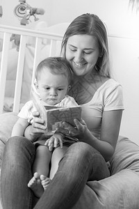 年轻母亲与婴儿一起坐在豆包和阅读书中的黑白年轻母亲肖像图片
