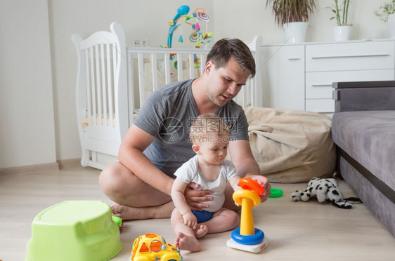 父亲和婴儿坐在地板上玩玩具图片
