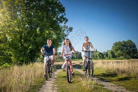 幸福的一家三口在草地上骑着自行车图片