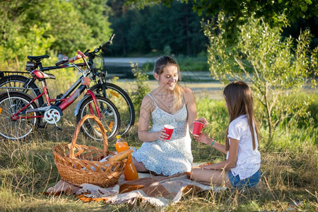 与10岁女儿在河边野餐的妇女图片