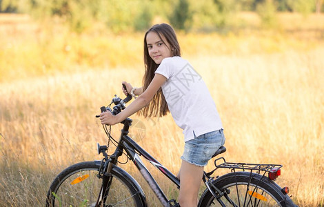 微笑的少女在野外骑自行车图片