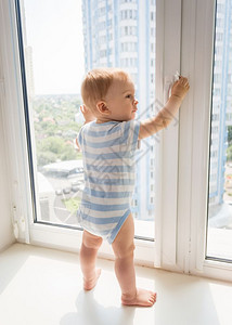 小宝男孩站在窗边拉着把手图片