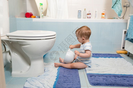 坐在浴室地板上玩卫生纸的可爱男孩图片