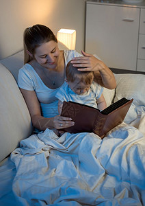 母亲在床上的给婴儿读童话书背景图片