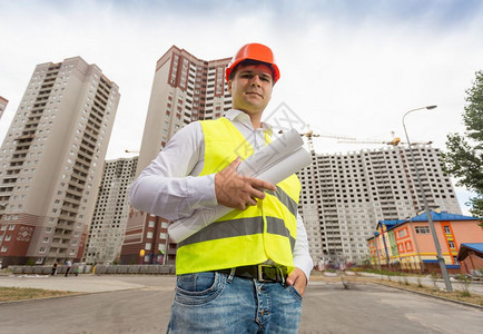 硬帽建筑工程师的肖像摆在刚建成的筑物前图片