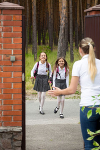 两个快乐的女孩放学后跑去找母亲背景图片