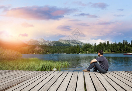 日落时坐在高山湖边的人图片