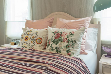 室内古老卧床上有花枕头和粉色条纹毯子图片