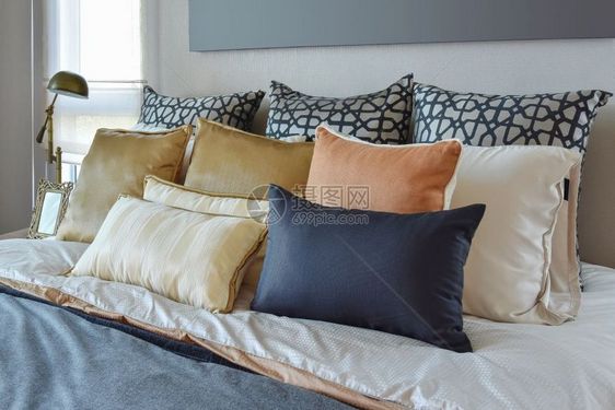 床上和边桌灯有橙子和金枕头的现代卧室内房图片
