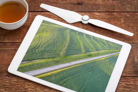 密苏里州有拖拉机脚印的绿大豆田检查数字平板电脑上的无人机空中作物图片图片