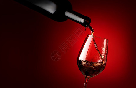 红酒倒在背景的葡萄酒杯中图片