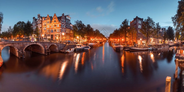 阿姆斯特丹运河和桥梁的夜间城市视图阿姆斯特丹运河桥梁和典型房屋船只和自行车的全景晚上清晨蓝色黄昏时段荷兰图片