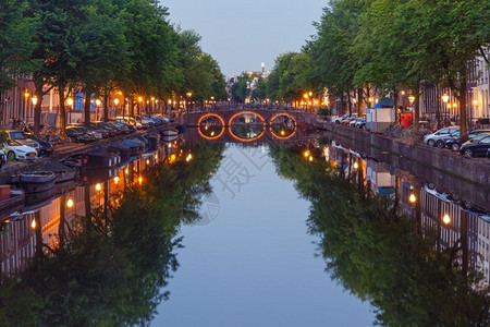 阿姆斯特丹运河和桥梁的夜间城市视图阿姆斯特丹运河桥梁和典型房屋船只和自行车上午蓝色时段荷兰图片